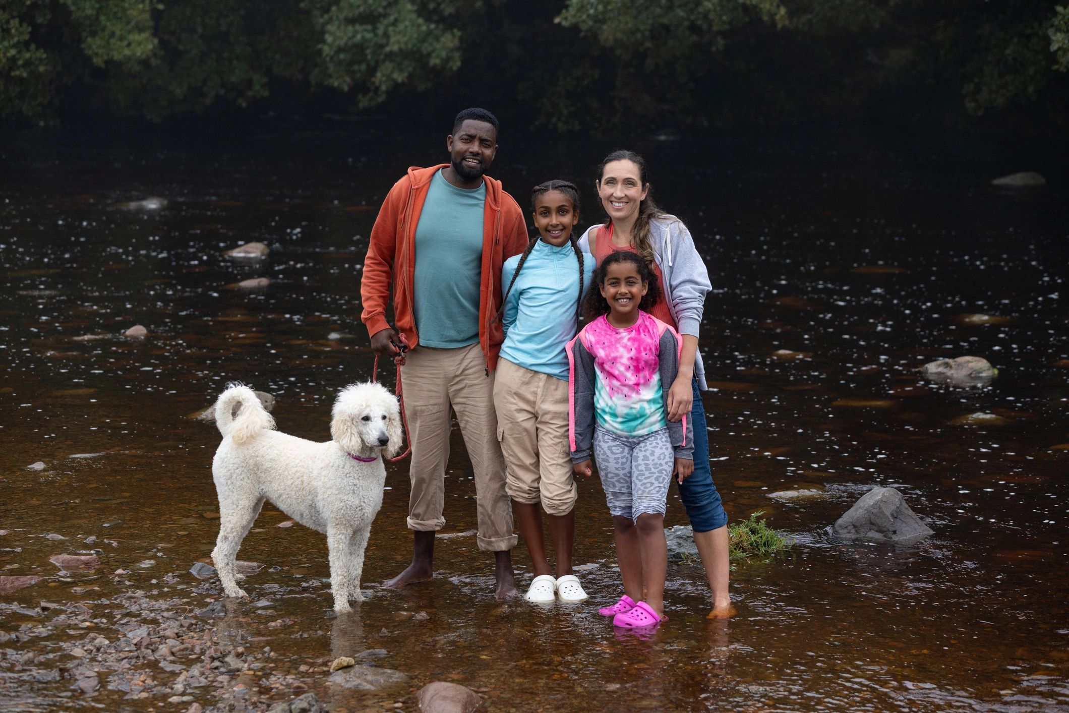 Family with dog standing in a river